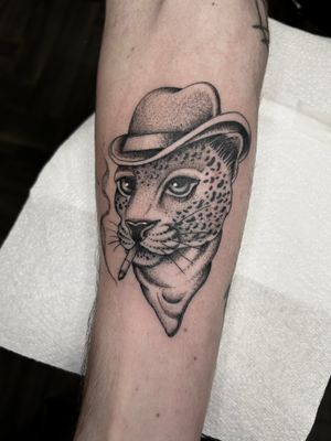 Check out this unique black and gray traditional tattoo of a leopard wearing a hat by Barney Coles!