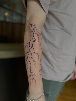 Get electrifying blackwork lightning bolt tattoo by Julia Bertholdi for a striking and powerful design.