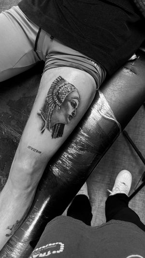 Experience the mesmerizing beauty of Cleopatra with this realistic black and gray tattoo by the talented artist Rollo.