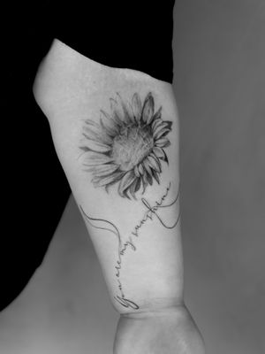 Beautiful black and gray sunflower tattoo with detailed small lettering by Saka Tattoo.