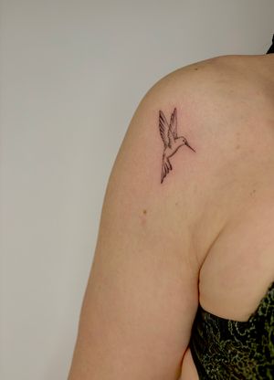 Admire the delicate beauty of this illustrative tattoo featuring a graceful hummingbird design by the talented artist, Ruth Hall.