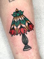 Experience the timeless beauty of a traditional flower and lamp tattoo by the talented artist Clara Colibri. Express your inner light and growth with this stunning design.