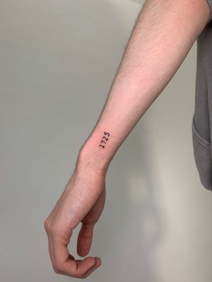 Elegant and minimal small lettering tattoo by Chloe Hartland. Perfect for a subtle and meaningful design.