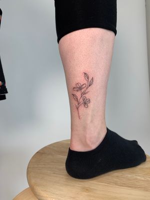 Get a dainty and beautiful flower tattoo by Chloe Hartland, known for her stunning fine line style.
