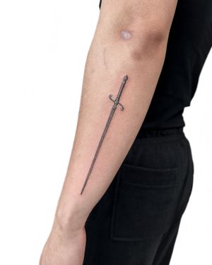 Discover the intricate details of this black and gray sword tattoo expertly executed by Alex Lloyd. Embrace the power and precision of the sword in this mesmerizing micro realism design.