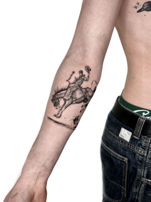 Capture the spirit of the Wild West with this detailed black and gray micro realism tattoo of a cowboy on a horse. Expertly crafted by tattoo artist Alex Lloyd.