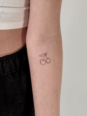 Get a dainty and elegant cherry tattoo by Saka Tattoo, featuring fine line details for a subtle and beautiful design.