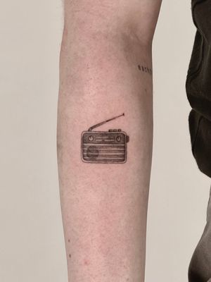 Get inked with this detailed black and gray illustrative tattoo of a classic radio stereo by Saka Tattoo.