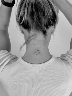 Get a dainty fine line tattoo of a wave and sun by Saka Tattoo for a minimalistic and elegant look.