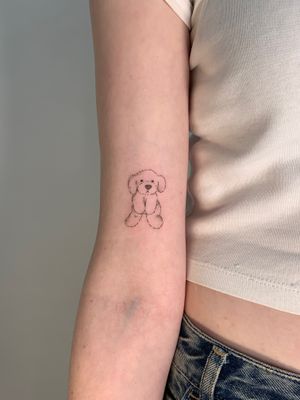 Illustrative tattoo of a dog plush toy, expertly executed by Chloe Hartland. Detailed fine line work brings this adorable motif to life.