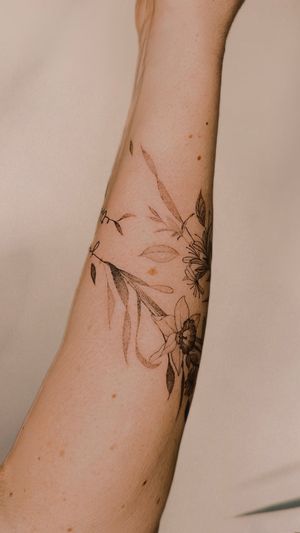 fine line wildflowers and birth flowers wrap around the forearm with the names of her children