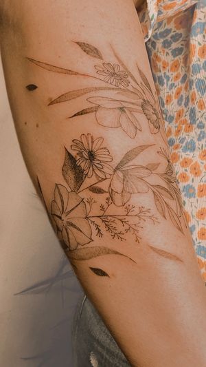 fine line wildflowers and birth flowers wrap around the forearm with names of her children
