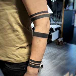 Blackwork bands on the arm with two thin blue lines