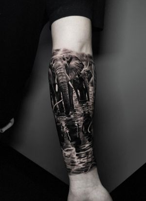 Experience the tranquility and beauty of nature with this stunning black and gray realism tattoo featuring an elephant in water.