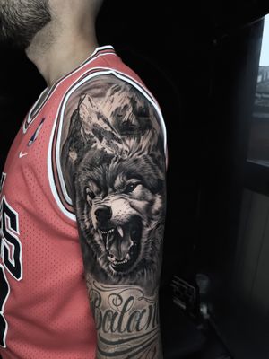 Realistic Wolf tattoo with mountains on the shoulder in black and grey style