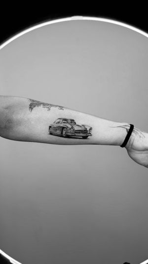 Experience the nostalgia of a classic car with this stunning black and gray micro-realism tattoo by Rollo.