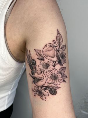 Beautiful tattoo by Michelle Harrison featuring a bird, tree, branch, blackberries, and leaves. A masterpiece of nature and art.