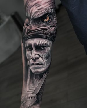 Black and gray realism tattoo of a native hunter man with an eagle, inspired by Aztec, Mayan, and Inca cultures, created by Ember.