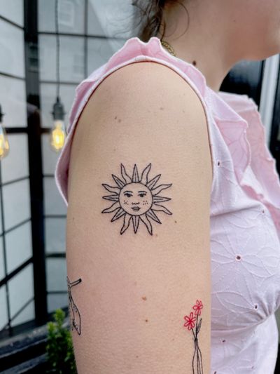 A minimalist hand-poked blackwork sun tattoo by Laura, radiating tranquility and warmth.