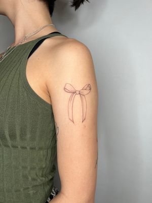 Adorn your skin with a fine line, illustrative bow tattoo expertly crafted by the talented artist Emma InkBaby.