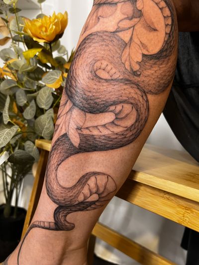 Elegant illustrative snake tattoo in black and gray, skillfully executed by Maria.