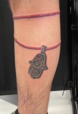 Detailed black and gray hamsa tattoo by Cara Hayward, featuring vibrant color accents, beautifully executed in micro-realism style.