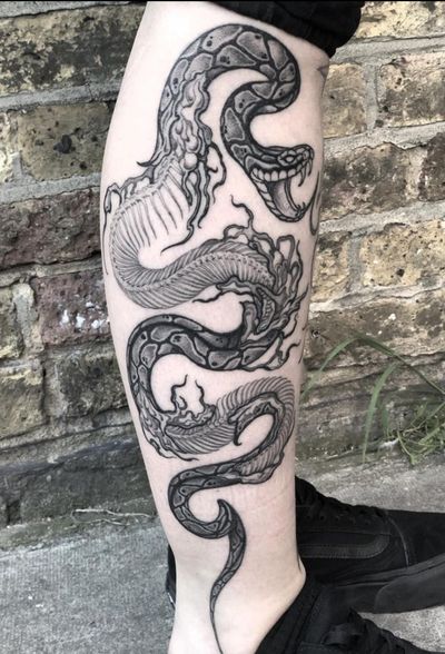 Capture the beauty of nature and death with this stunning illustrative tattoo featuring a snake intertwined with a skeleton, designed by the talented artist Amandine Canata.