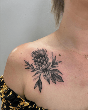 An illustrative black and gray tattoo by Alice Hope Tattoo featuring a detailed thistle plant in full bloom.