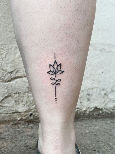 Beautiful blackwork and fine line hand-poked tattoo by Laura featuring a lotus flower and unalome motif in an ornamental style.