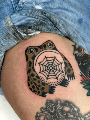 Illustrative tattoo of a cute frog surrounded by a spider web, designed by Jakob Isaac.