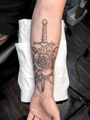 Get a stunning floral and dagger tattoo in woodcut style by the talented artist Alexandra Mulhall.