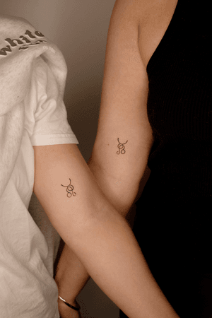 Fine line tattoo of matching zodiac symbols for couples by Winnie Shwe.