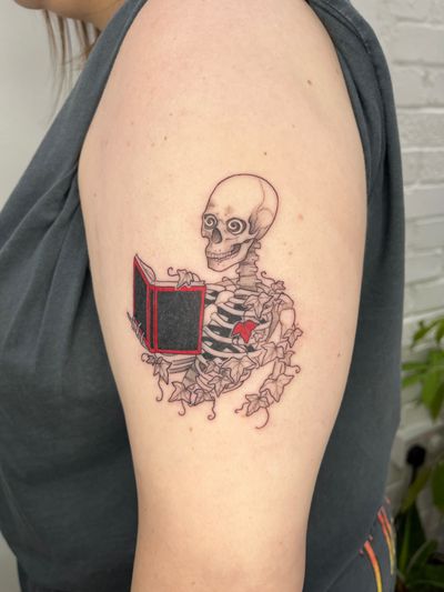 A fine line illustrative tattoo by Michelle Harrison featuring a skeleton holding a book, intricate and detailed design.