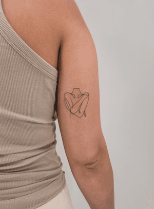 Abstract fine line tattoo of a singleline woman hugging herself, symbolizing self love and empowerment.