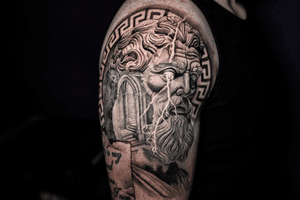 A realistic tattoo of Zeus from Greek mythology, expertly done by Warren Mullins in black and gray ink.