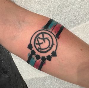 Get a unique music tattoo featuring the iconic Blink 182 band logo in blackwork and watercolor style, done by artist Katy Sarsfield.