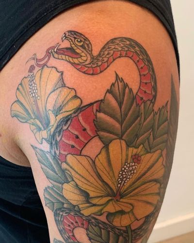 Vibrant neo-traditional tattoo featuring a colorful snake wrapped around a blooming flower, showcasing intricate illustrative details. Located in New York, US.