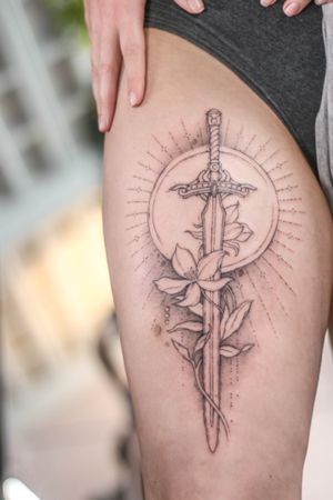 Get inspired by this illustrative tattoo featuring a unique combination of a sun, flower, and sword, expertly done by artist George Francis.