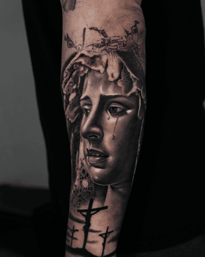 Realistic black and gray tattoo featuring a woman with a holy cross, embodying religious symbolism. By artist Ember.