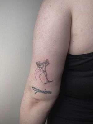 Elegant black and gray illustrative tattoo of a hand holding a chalice, done by Alina Amberland.