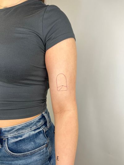 Capture the tranquil beauty of a desert dune through a window in this illustrative fine line tattoo by Emma InkBaby.