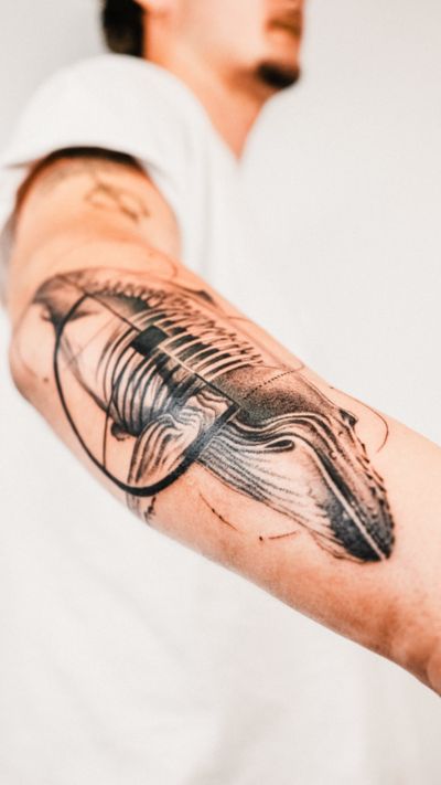 Gabriele Edu's fine line blackwork tattoo features an abstract geometric interpretation of a whale in a sleek and modern design.