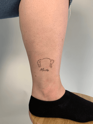 Fine line tattoo of a small dog outline, by Chloe Hartland, perfect for pet lovers.