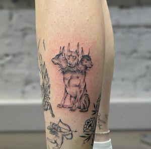A beautifully detailed black and gray illustrative tattoo of the mythical three-headed dog, Cerberus. Created by tattoo artist Ellie Shearer.