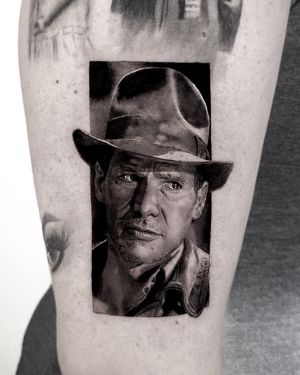 Capture the essence of Harrison Ford as Indiana Jones in this detailed black and gray tattoo by Jay Soze.