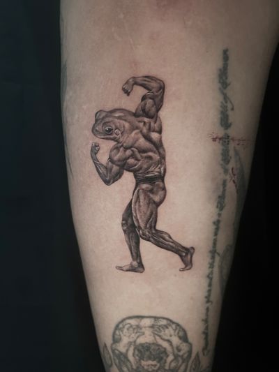 Get inked with a detailed black and gray illustration of a frog bodybuilder flexing double biceps by artist Lauren.