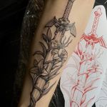 Black and gray neo-traditional tattoo of the iconic master sword from Zelda, done by Kat Jennings, featuring intricate floral elements.