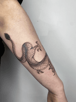 Get a stunning black and gray dragon tattoo with intricate details by the talented artist Charlie Macarthur.