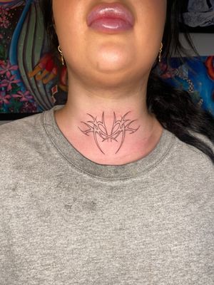 Explore the bold and intricate neotribal design by artist Beth Farbrother on this stunning throat tattoo.