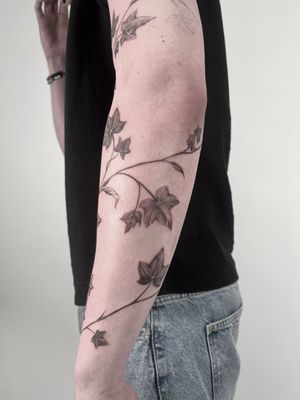 Embrace the beauty of nature with this elegant black and gray branch, vine, and leaf tattoo by Lauren.